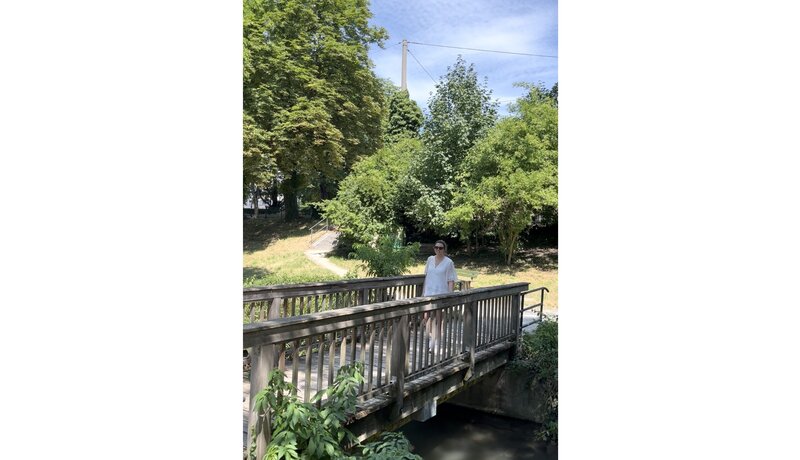 Frau auf Holzbrücke in einer grünen Parklandschaft in Augsburg  | © Ringhotels e.V., SK