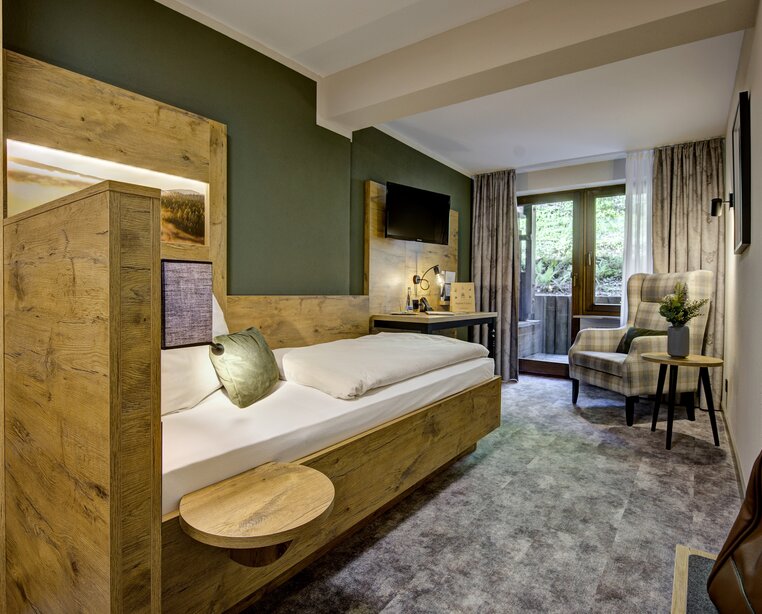 Modernes Einzelzimmer mit rustikalen Holzmöbeln und Balkon im Ringhotel Sonnenhof in Baiersbronn, einem 4-Sterne-Hotel im Schwarzwald. | © Ringhotel Sonnenhof in Baiersbronn