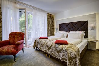 Elegantes Doppelzimmer mit Balkonzugang und Blick ins Grüne im Ringhotel Sonnenhof in Baiersbronn, einem 4-Sterne-Hotel im Schwarzwald. | © Ringhotel Sonnenhof in Baiersbronn