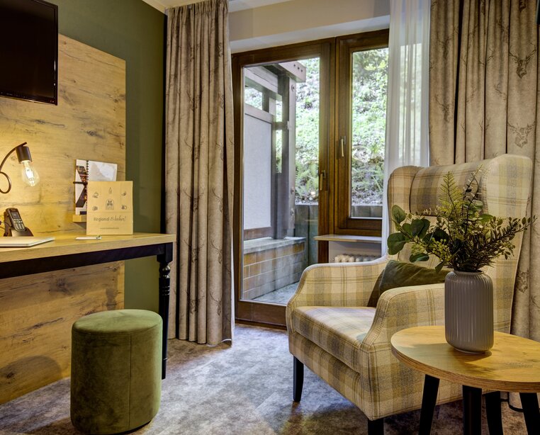 Gemütliche Leseecke mit Sessel und Schreibtisch am Balkon in einem Einzelzimmer im Ringhotel Sonnenhof in Baiersbronn, einem 4-Sterne-Hotel im Schwarzwald. | © Ringhotel Sonnenhof in Baiersbronn
