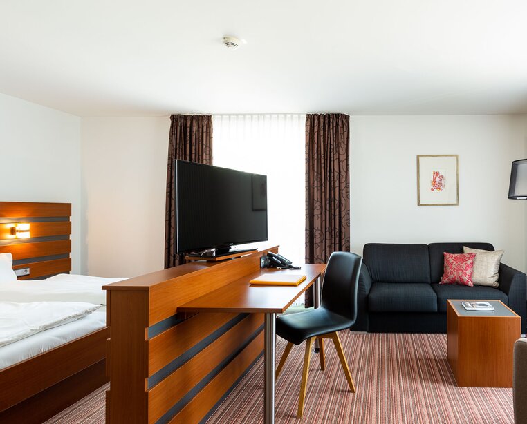 JuniorSuite with double bed, sofa and TV at Ringhotel sKreuz in Steinheim, 4 stars hotel | © Ringhotel sKreuz Steinheim